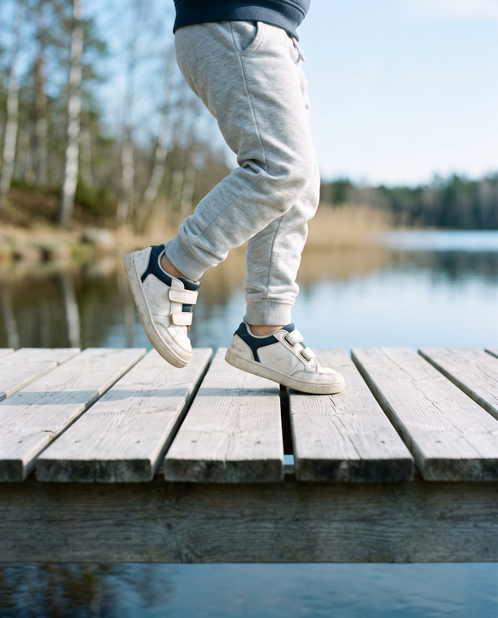 Barn hoppar på en brygga i bekväma sneakers med kardborre