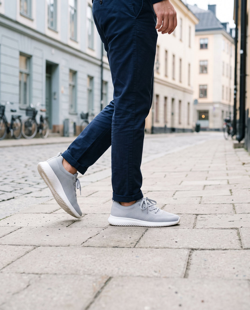 Man i grå stickade sneakers på en gata i Stockholm